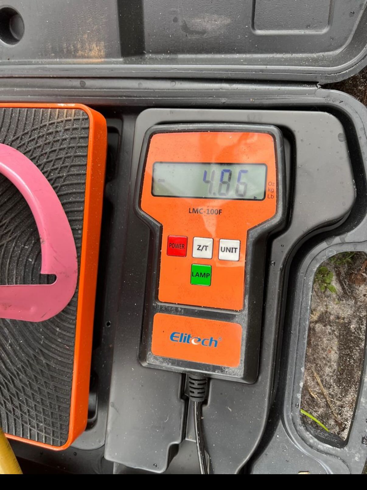 An orange Elitech digital refrigerant scale showing a reading of 4.86 in a black carrying case.