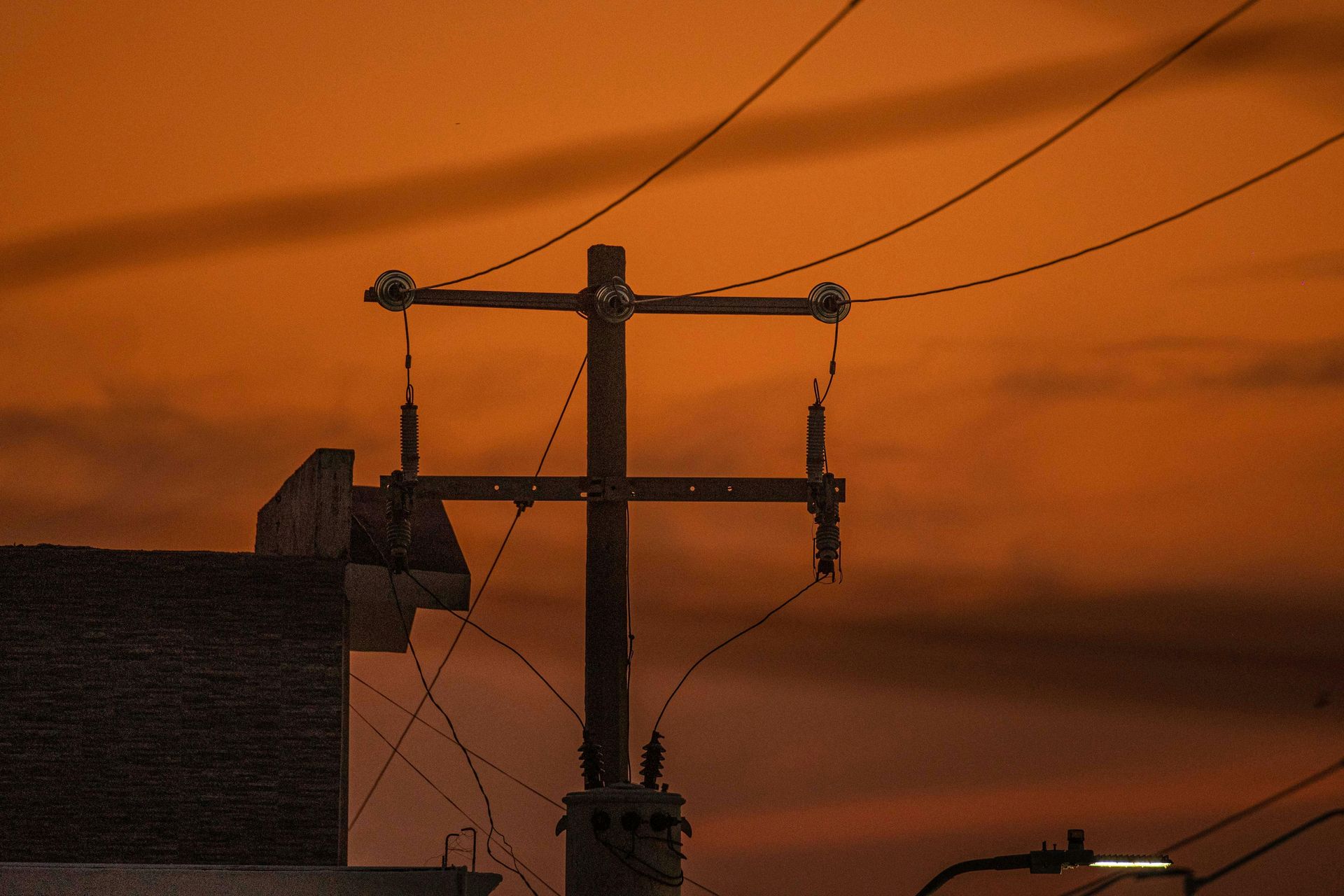 Utility pole with wires against an orange-hued sky.