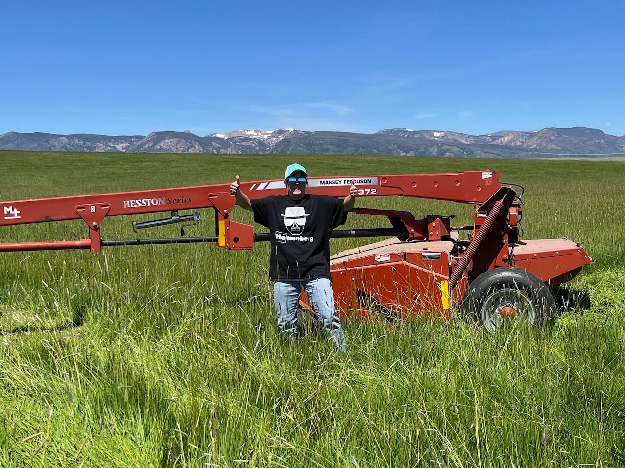 A man is standing in a field next to a tractor.