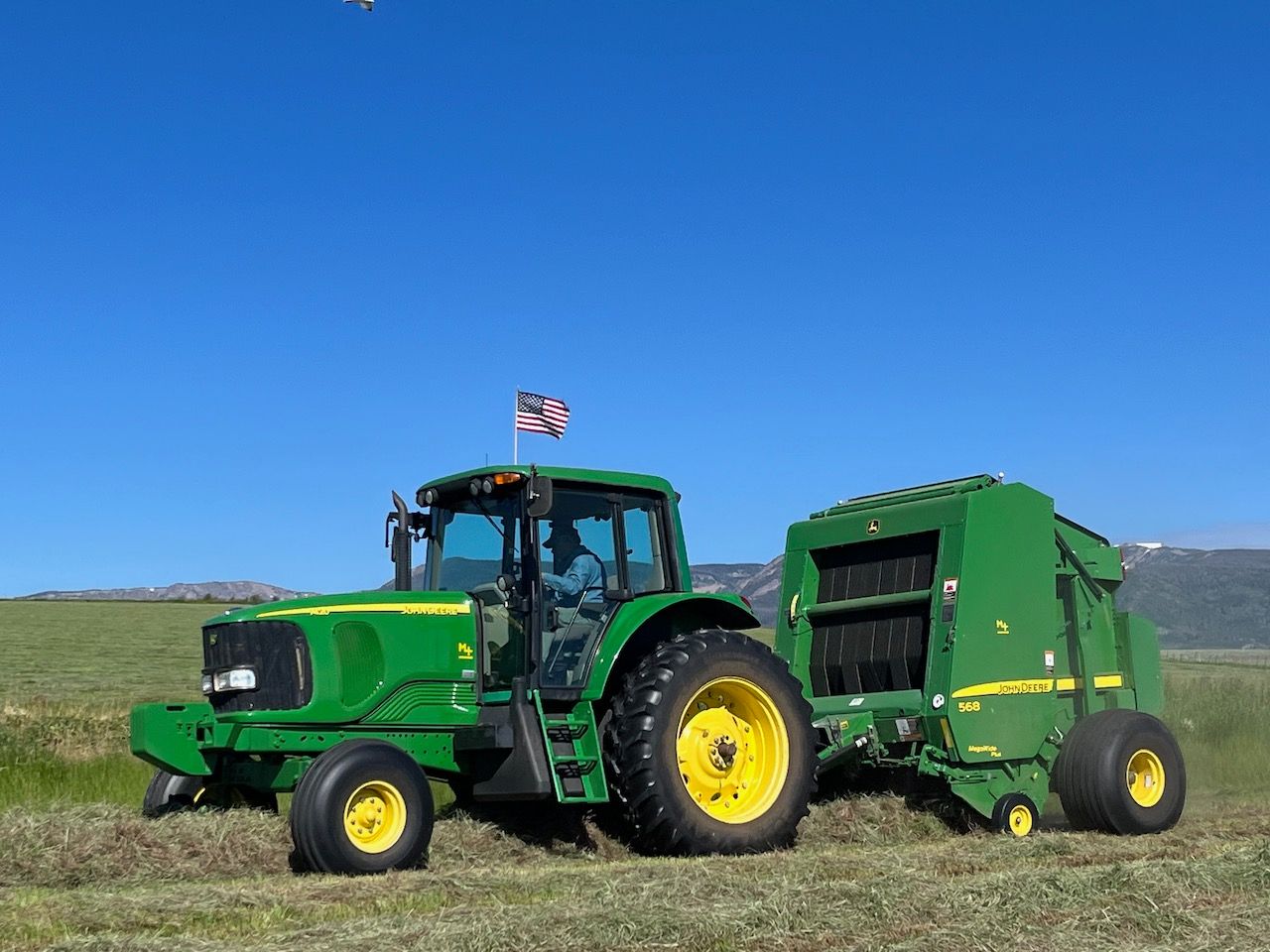 A john deere tractor with a hay baler attached to it