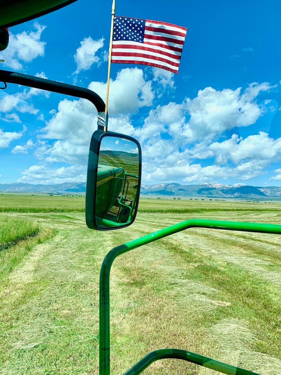 An american flag is hanging from the side of a tractor.