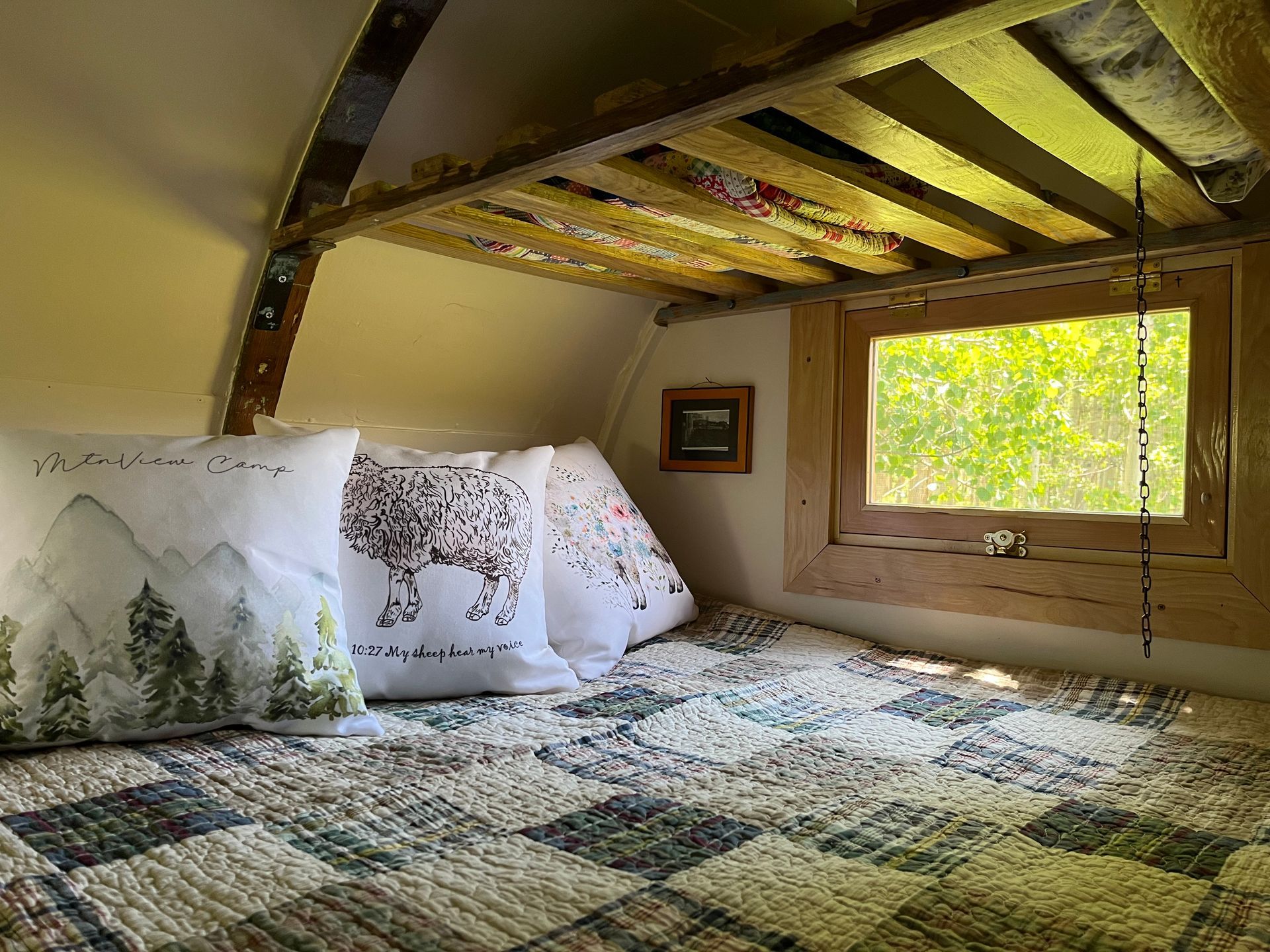 A sheepwagon bedroom with a bunk bed and a window.
