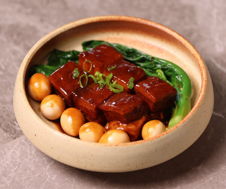 Steamed buns with meat filling in a bamboo steamer basket on a white plate
