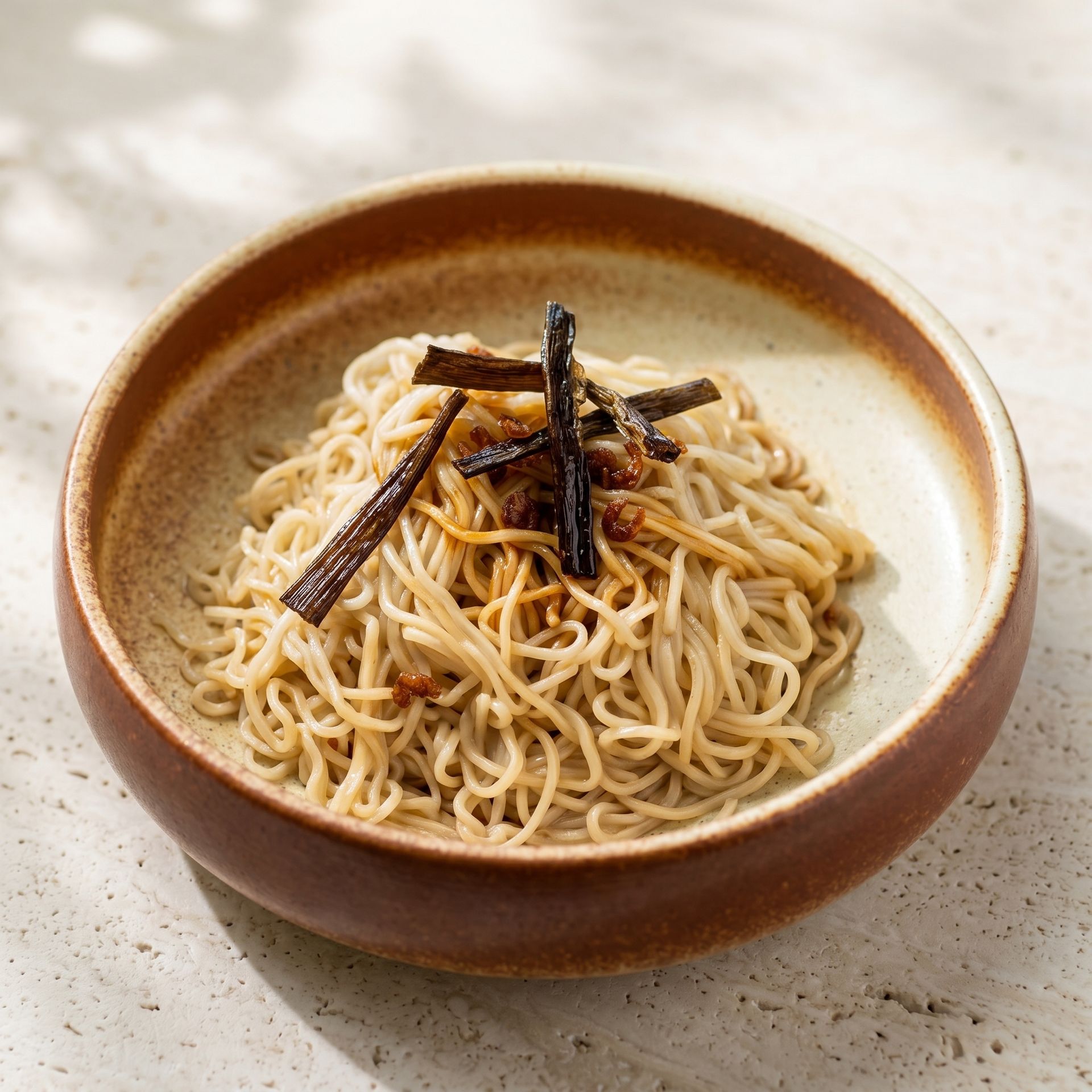 Bowl of plain noodles topped with dark seaweed strips on a light countertop