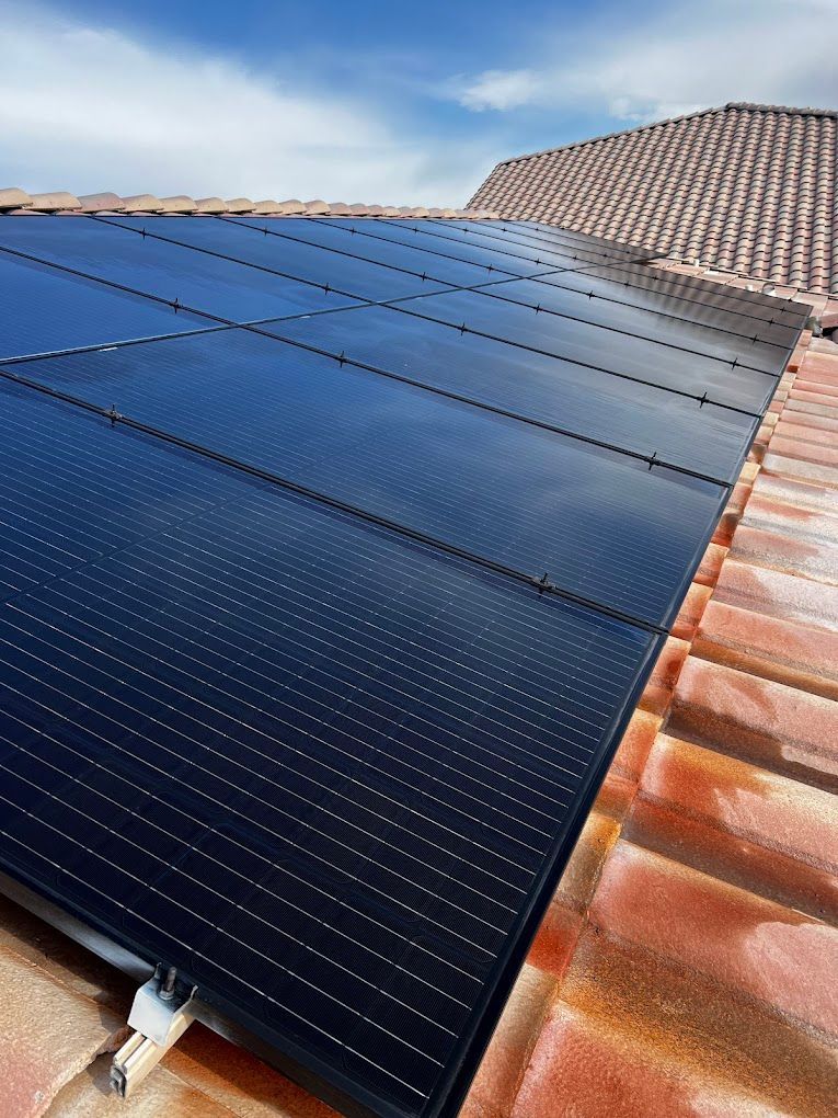 There are many solar panels on the roof of a house.