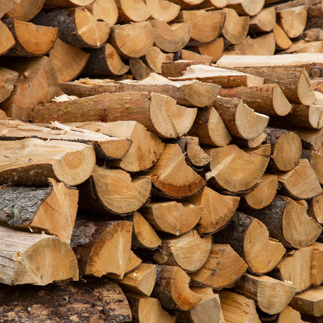 Pile of split firewood, cut ends visible, stacked outdoors.