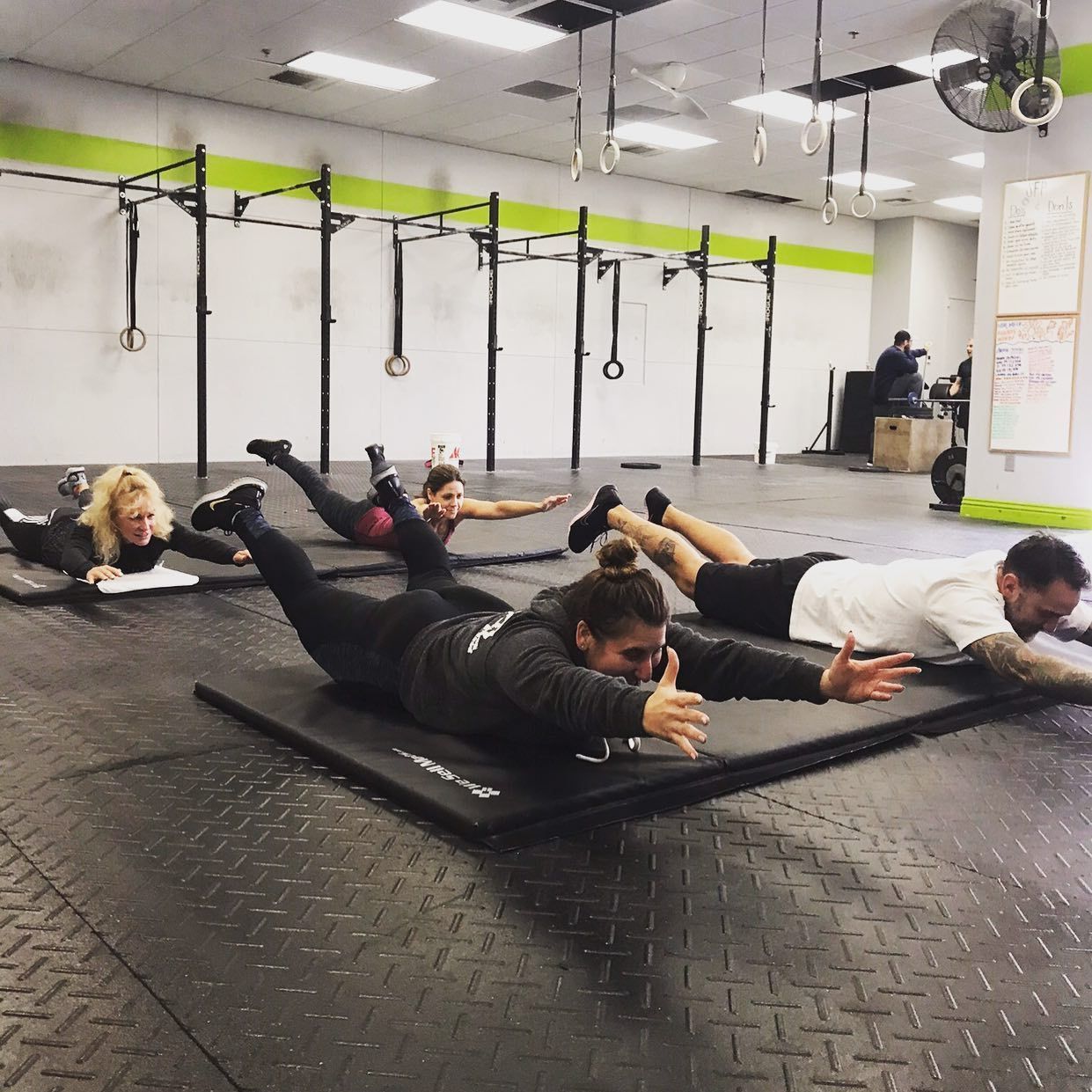 A group of people are doing exercises on mats in a gym