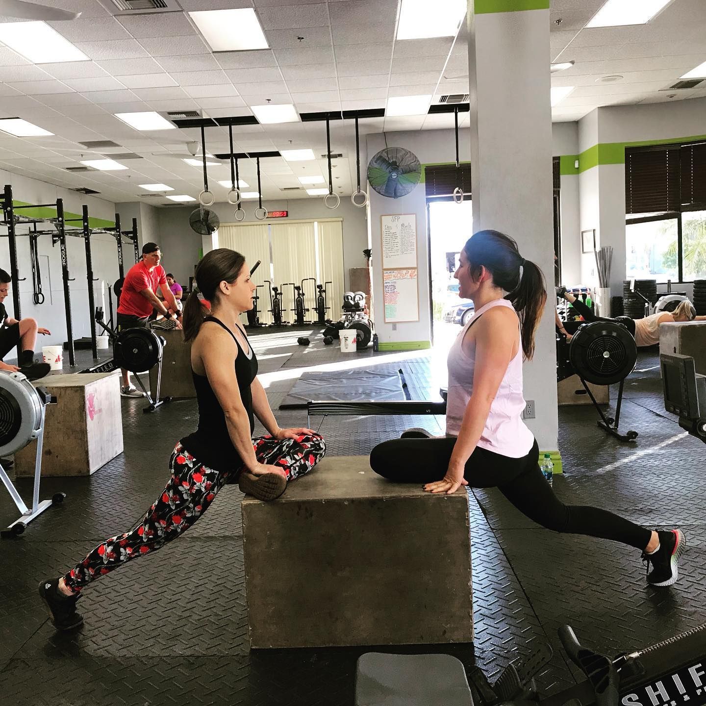 Two women are doing stretching exercises in a gym.