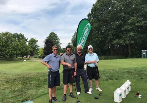 A group of men are standing on a golf course holding golf clubs.