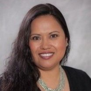 A woman wearing a scarf and a black jacket is smiling for the camera.