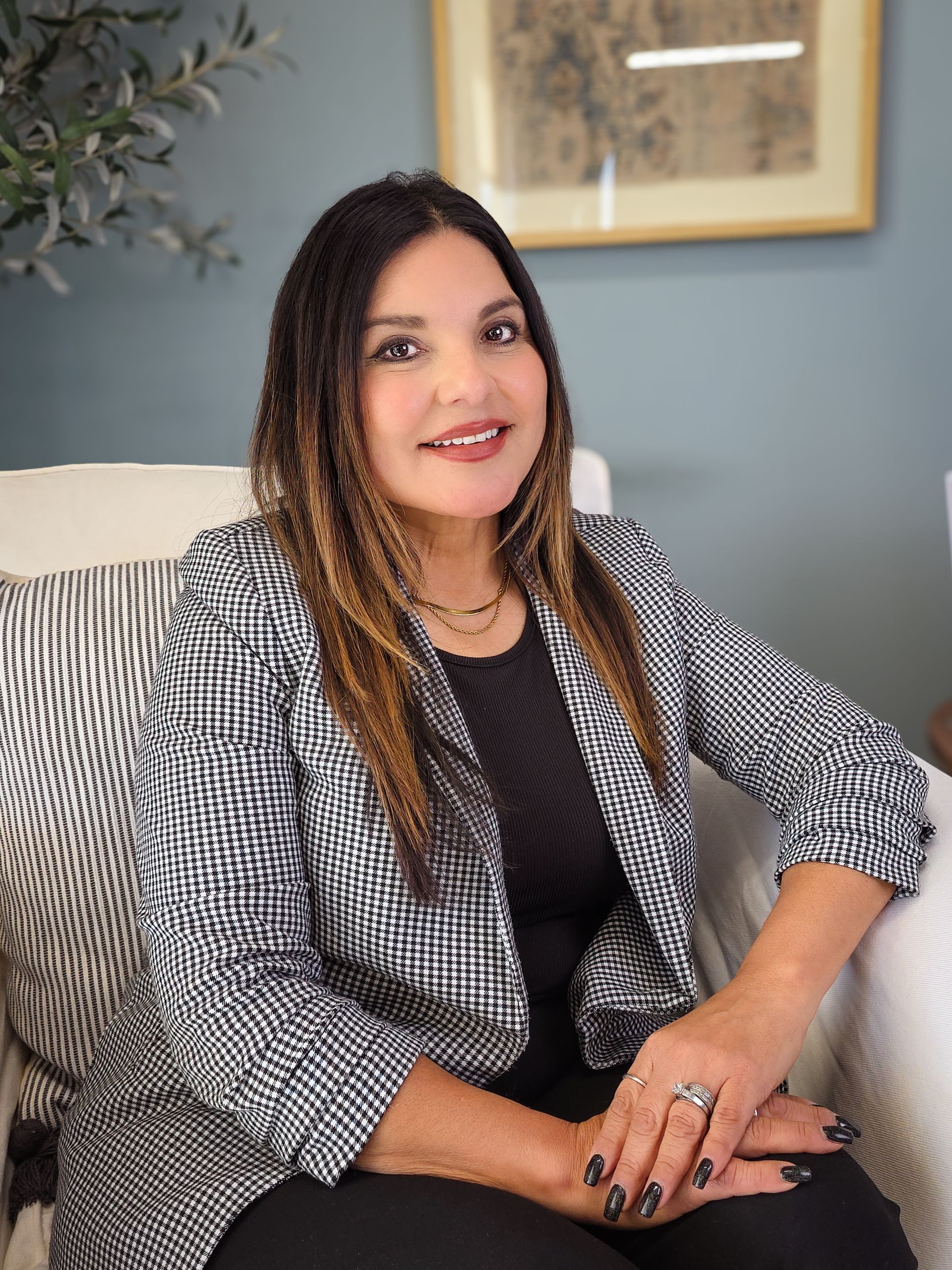 A woman with long black hair is standing in front of a window.