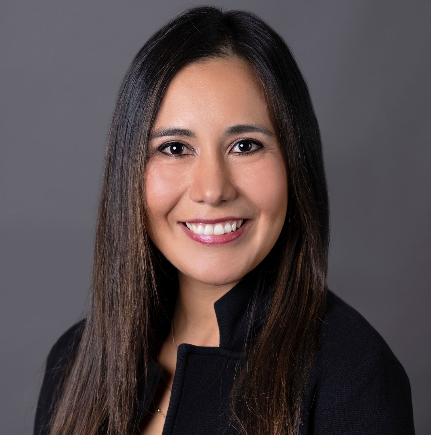 A woman in a black jacket is smiling for the camera