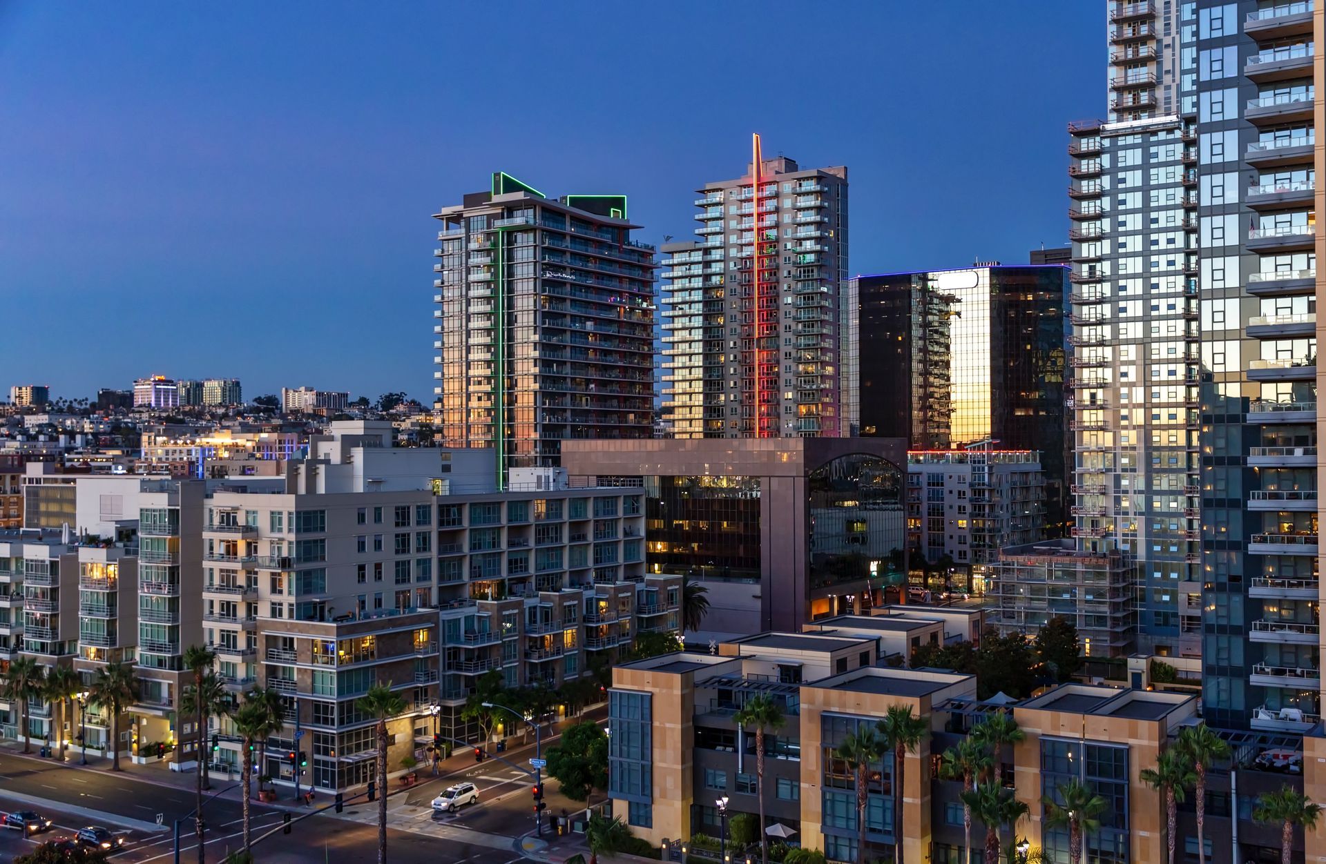 City skyline at dusk with high-rise buildings reflecting sunlight and a clear blue sky.