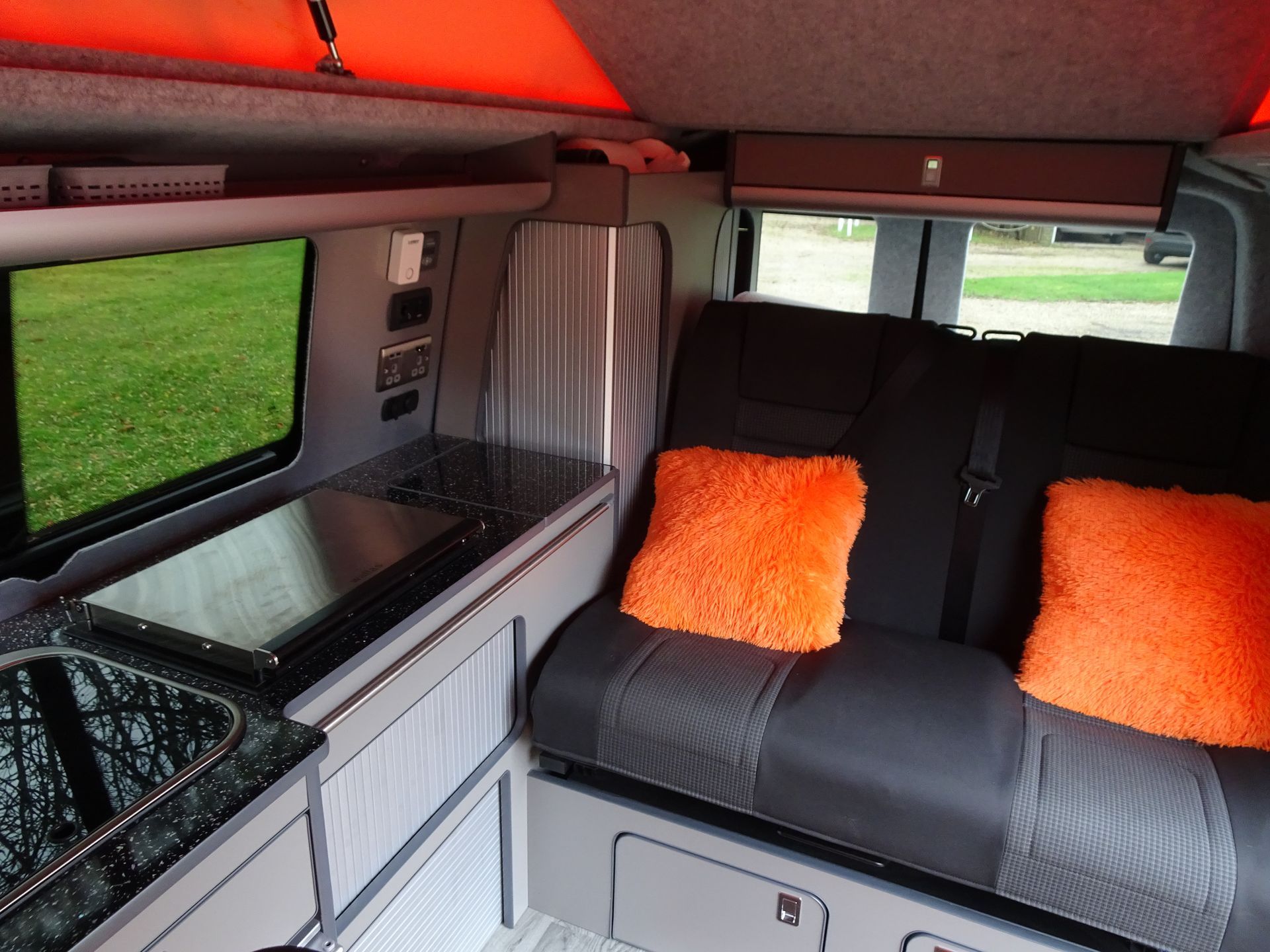 The inside of a van with a couch and orange pillows
