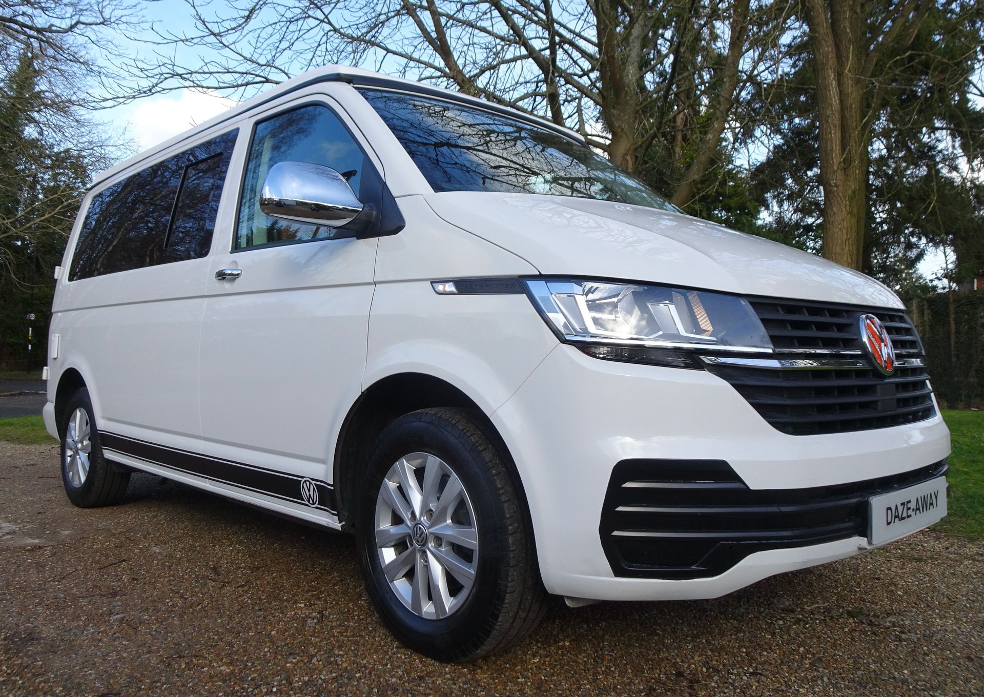 A white van is parked on a gravel road.
