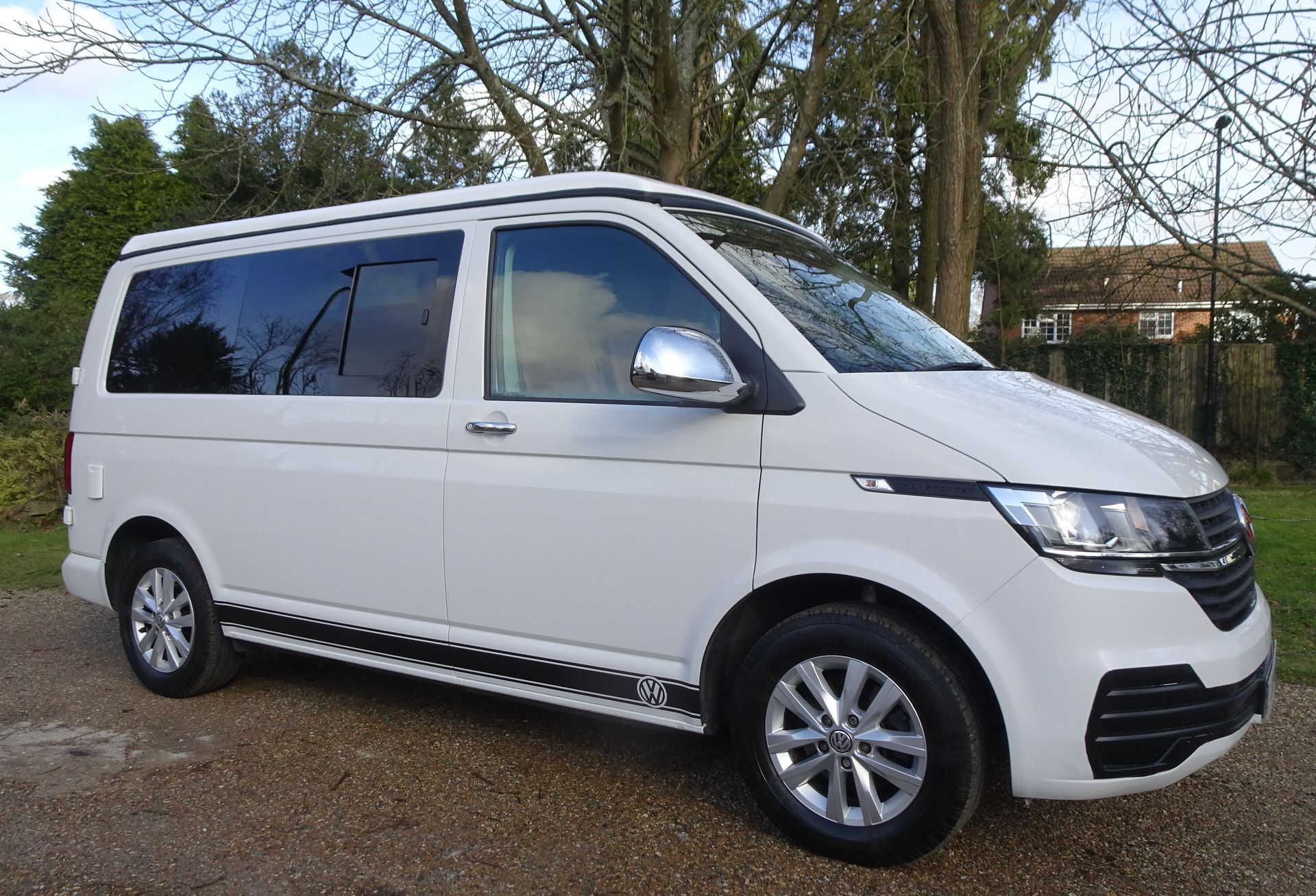 A white van is parked on a gravel road.