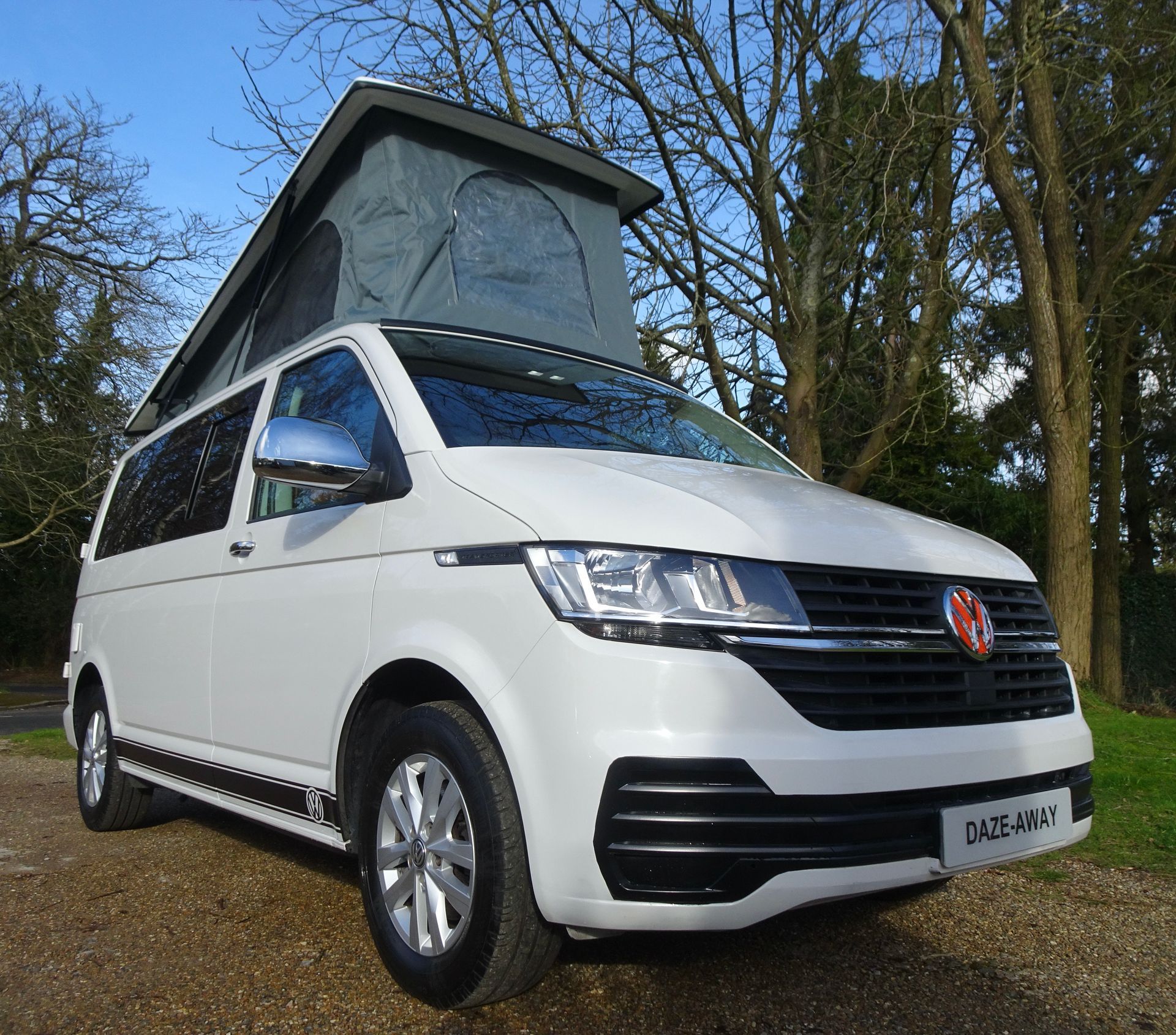 a white van with a pop up roof is parked on the side of the road .