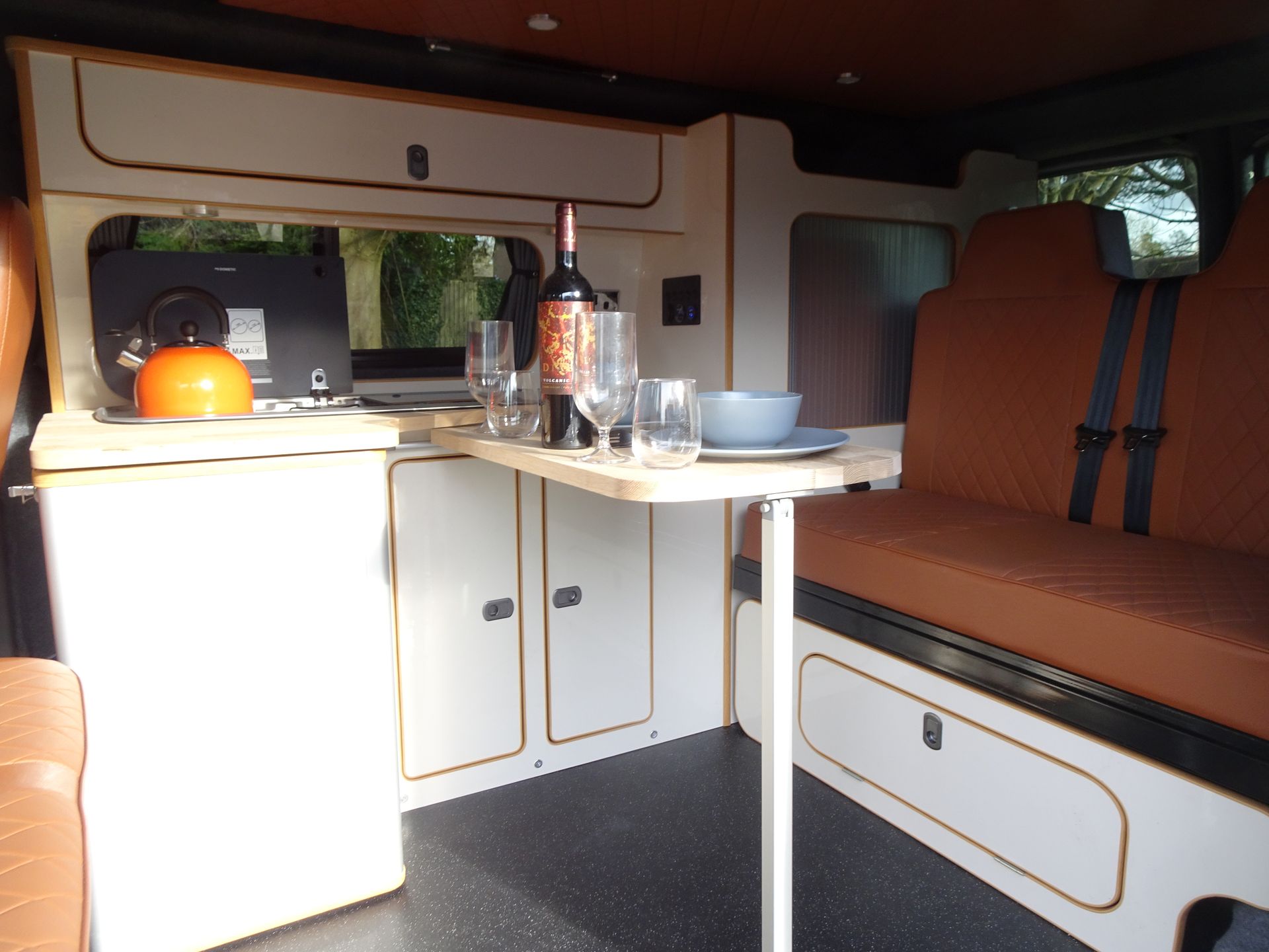 A camper van with a table and a bottle of wine on it