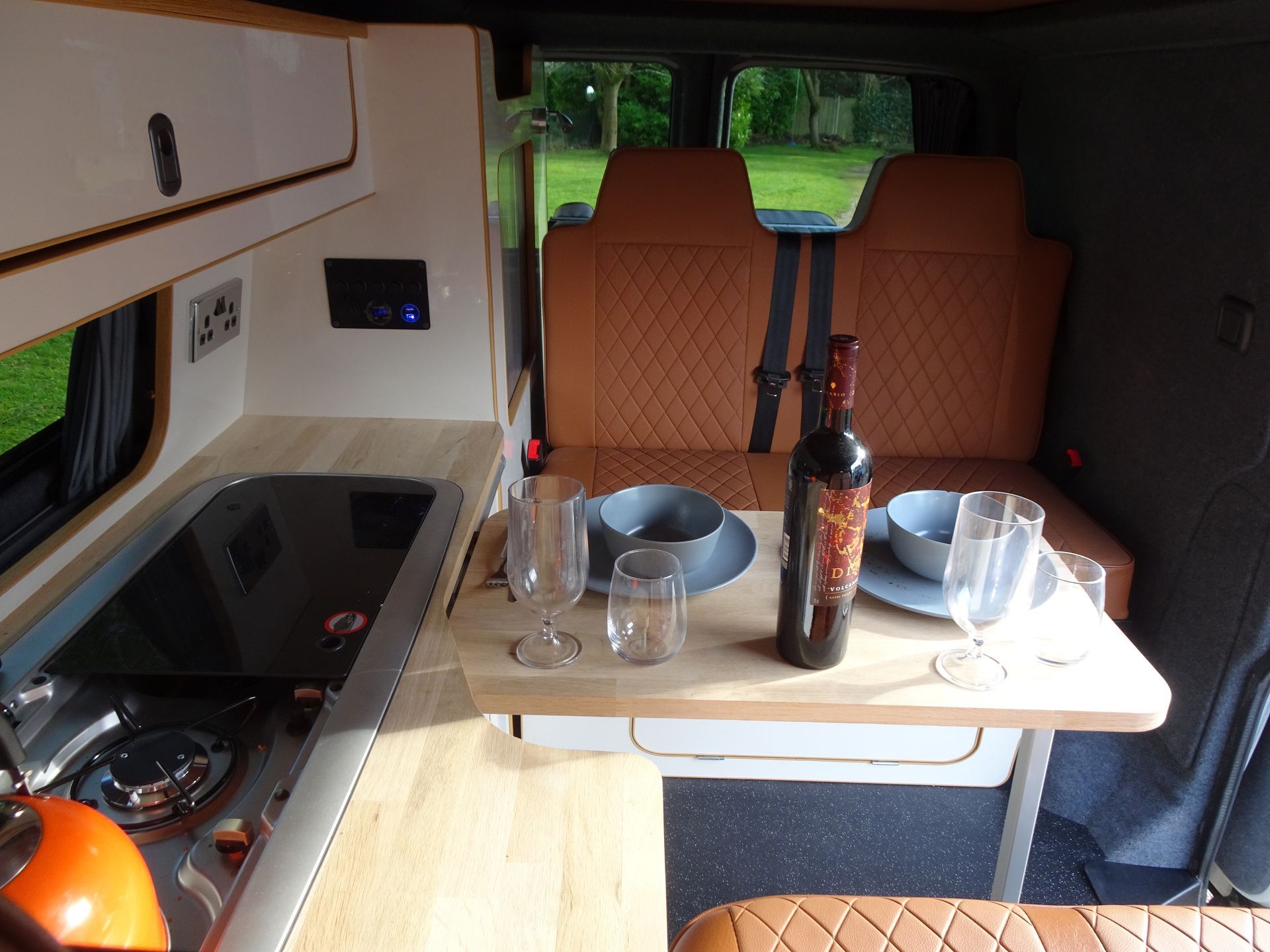 The inside of a van with a table and a bottle of wine on it.