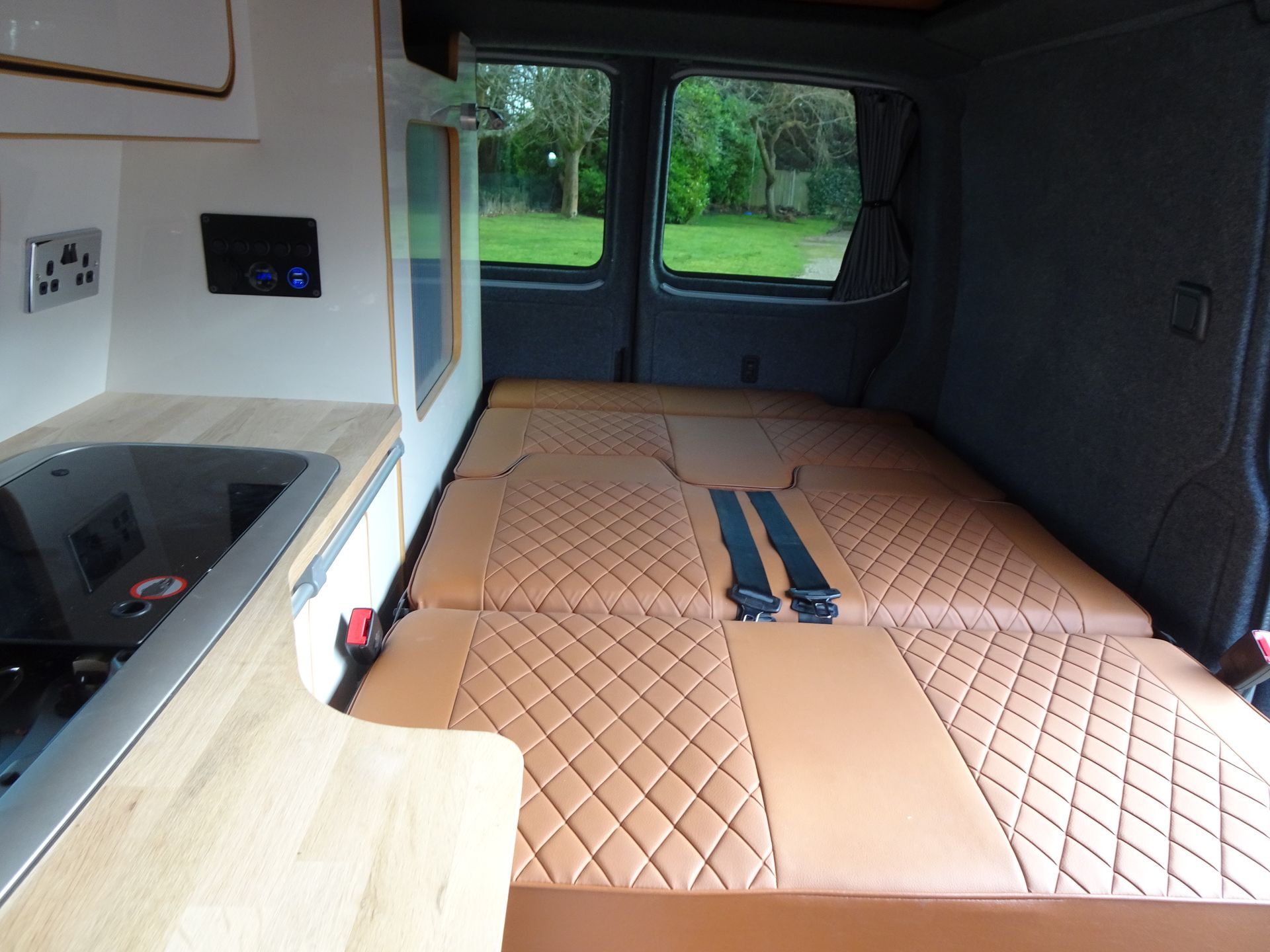 The inside of a van with a bed and a kitchen