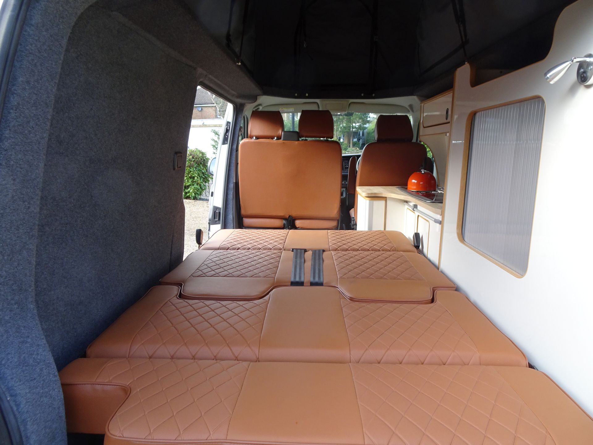 The inside of a van with brown seats and a bed