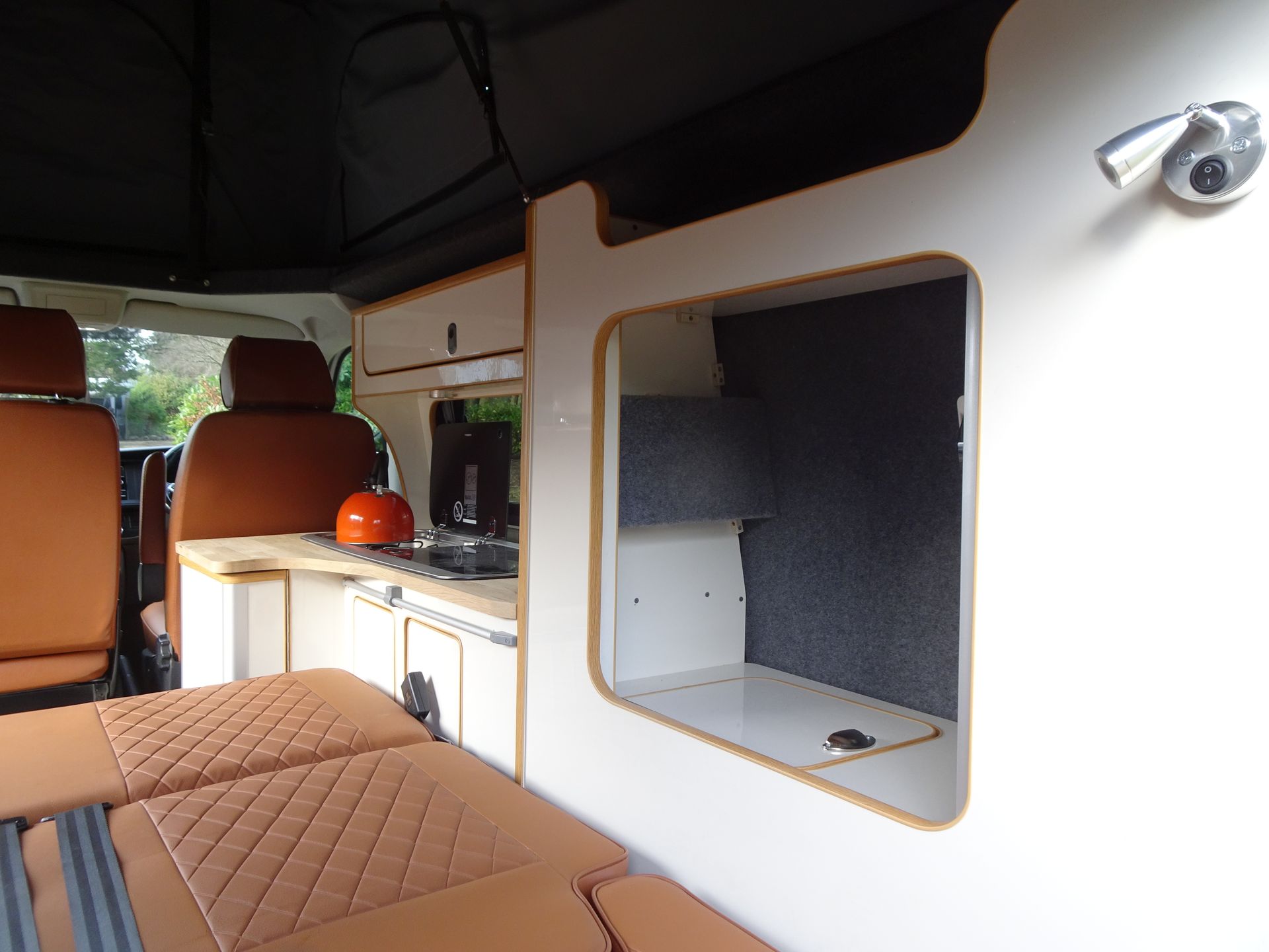 The inside of a camper van with brown seats and a sink.