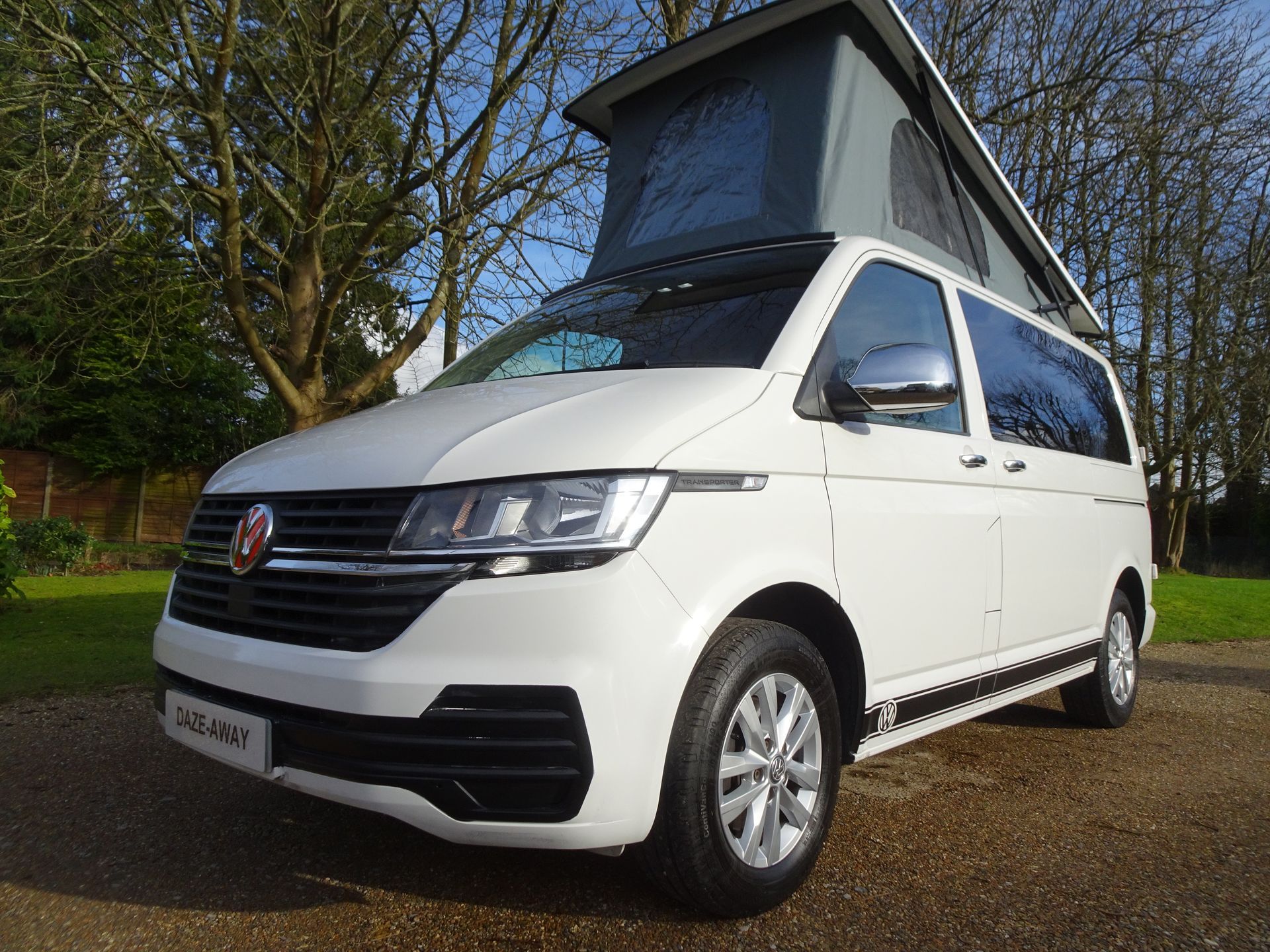 a white van with a pop up roof is parked on the side of the road .