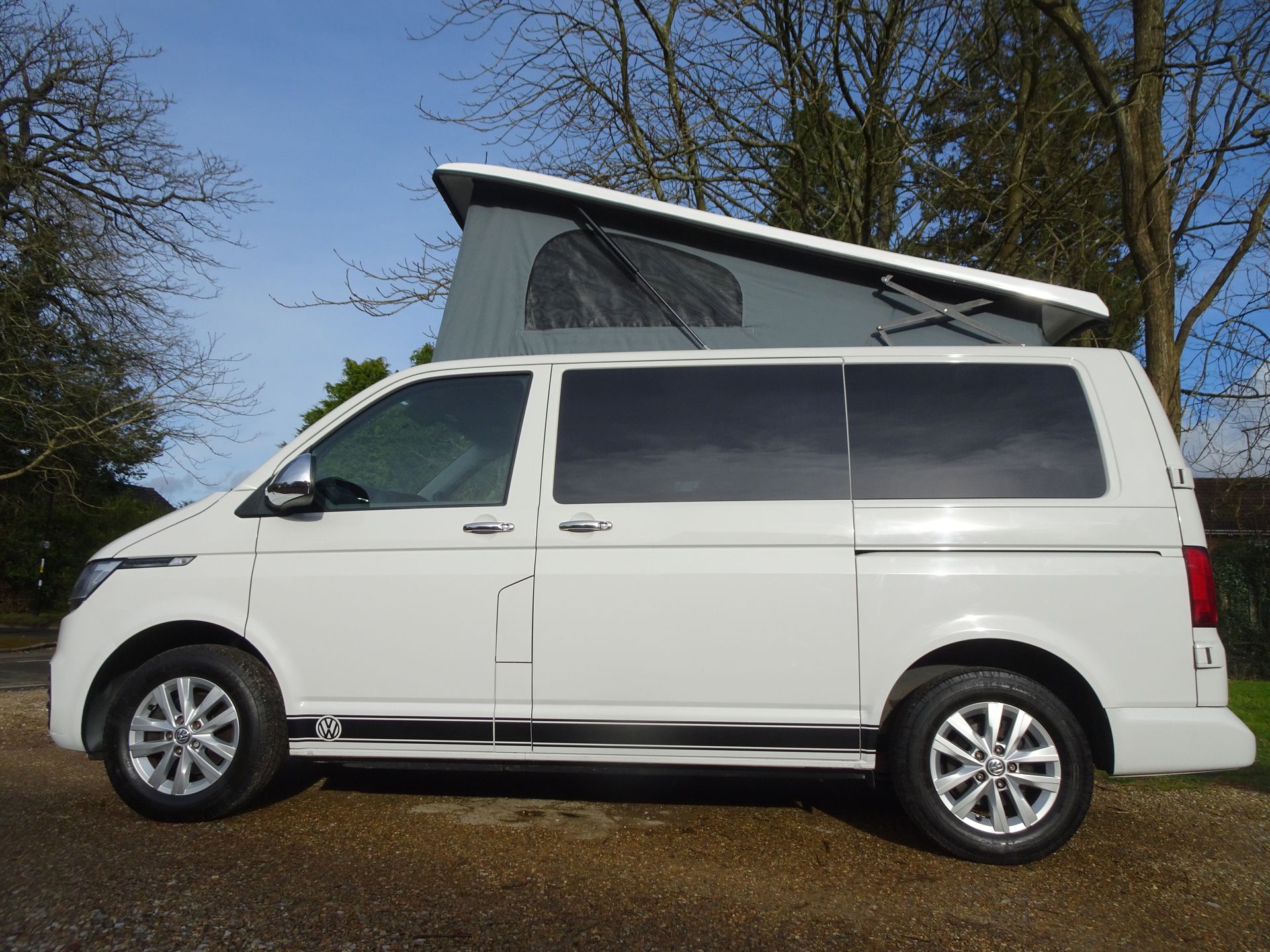 A white van with a pop top roof is parked in a parking lot.