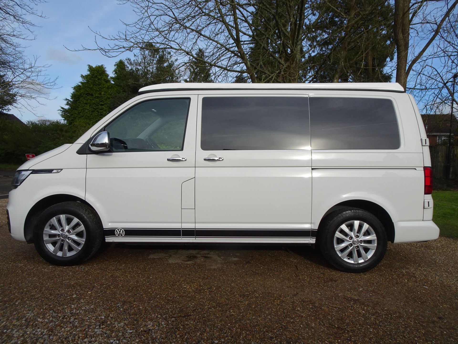 A white van is parked on a gravel road.