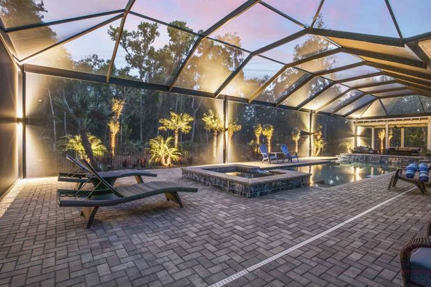 There is a swimming pool in the backyard with a screened in area.