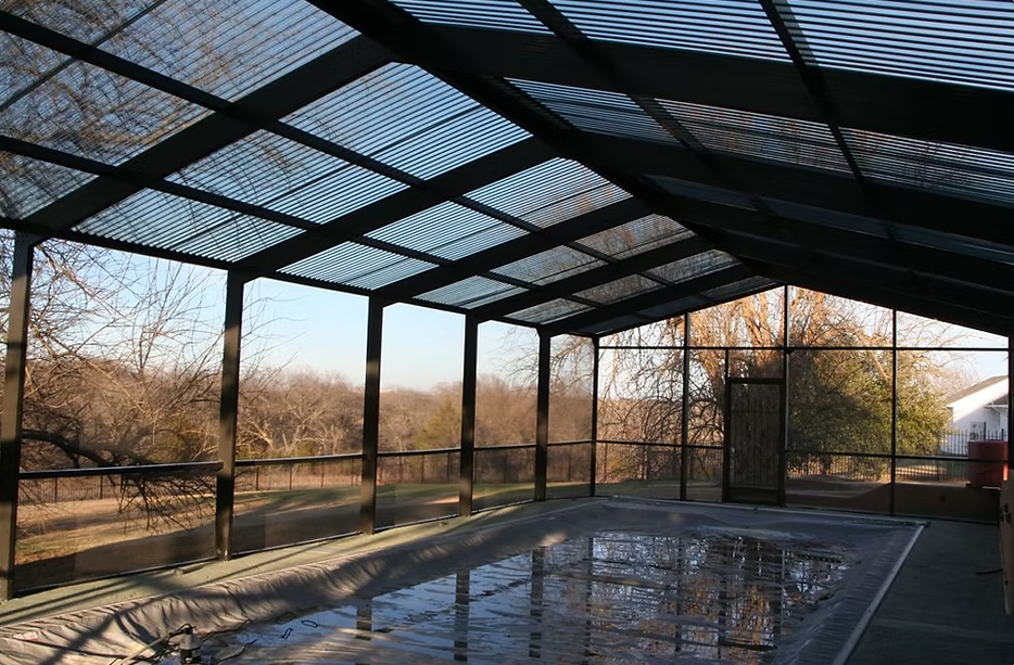 A screened in porch with a swimming pool in the background