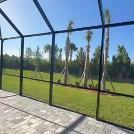 A screened in porch with a swimming pool in the background