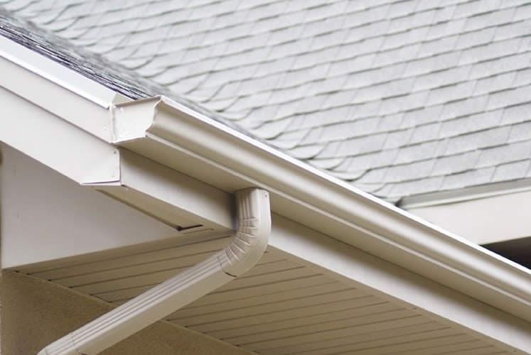 A close up of a white gutter on a roof of a house.