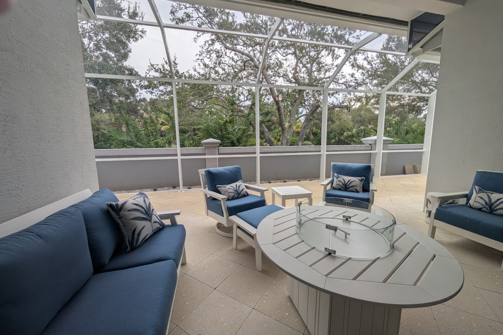 A screened in porch with a couch and ottoman and a view of a pool.