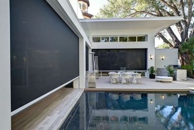 A screened in porch with a couch and ottoman and a view of a pool.
