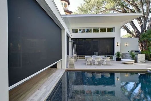 A screened in porch with a brick house in the background.