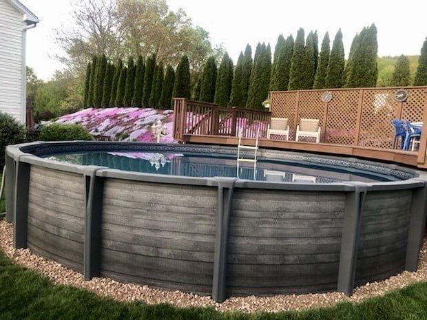 There is a swimming pool in the backyard with a screened in area.