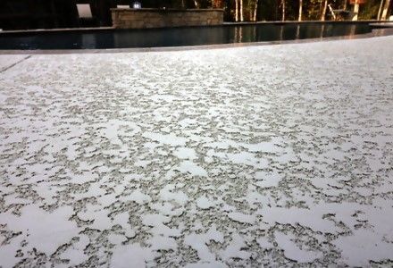 A screened in porch with a swimming pool in the background