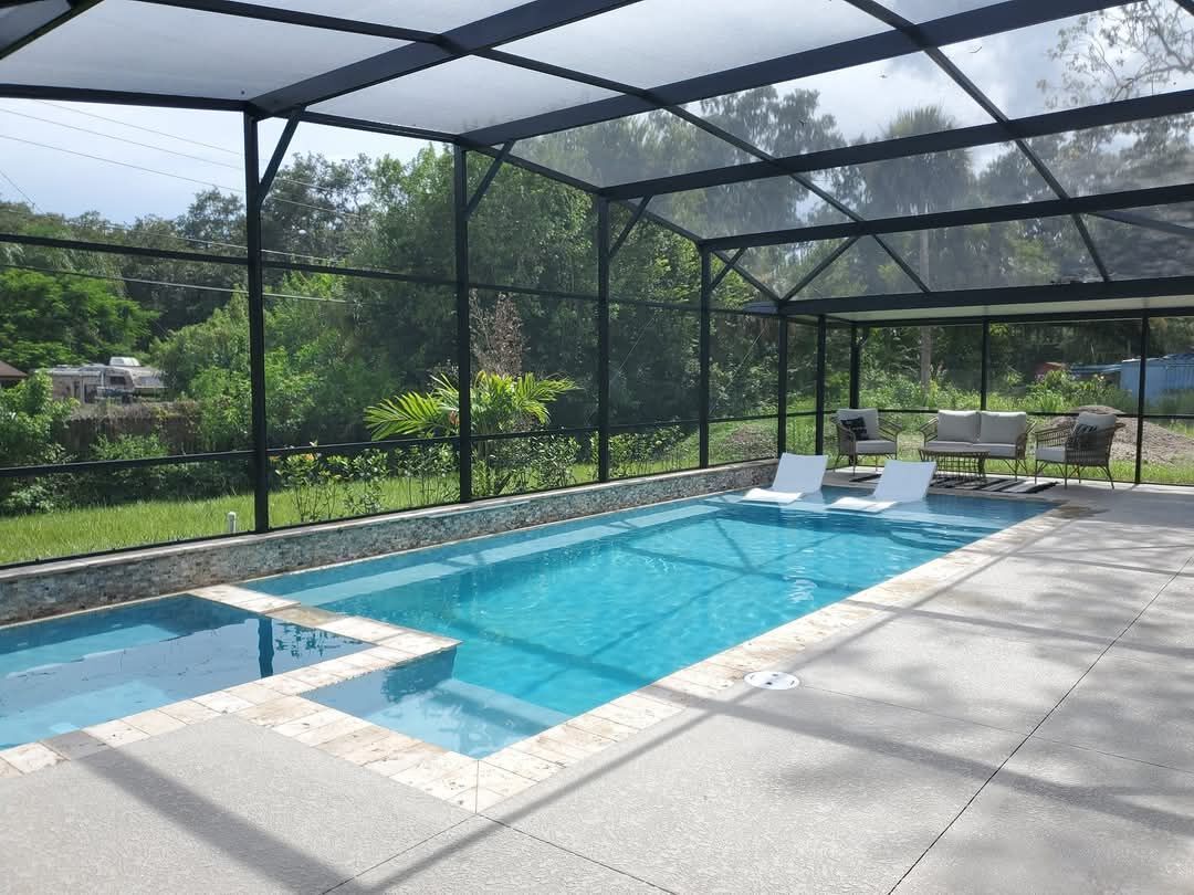 Custom concrete pool with glass mosaic tile and integrated spa inside a screen enclosure in Palm Bay, Florida, by Right Way Enclosures.