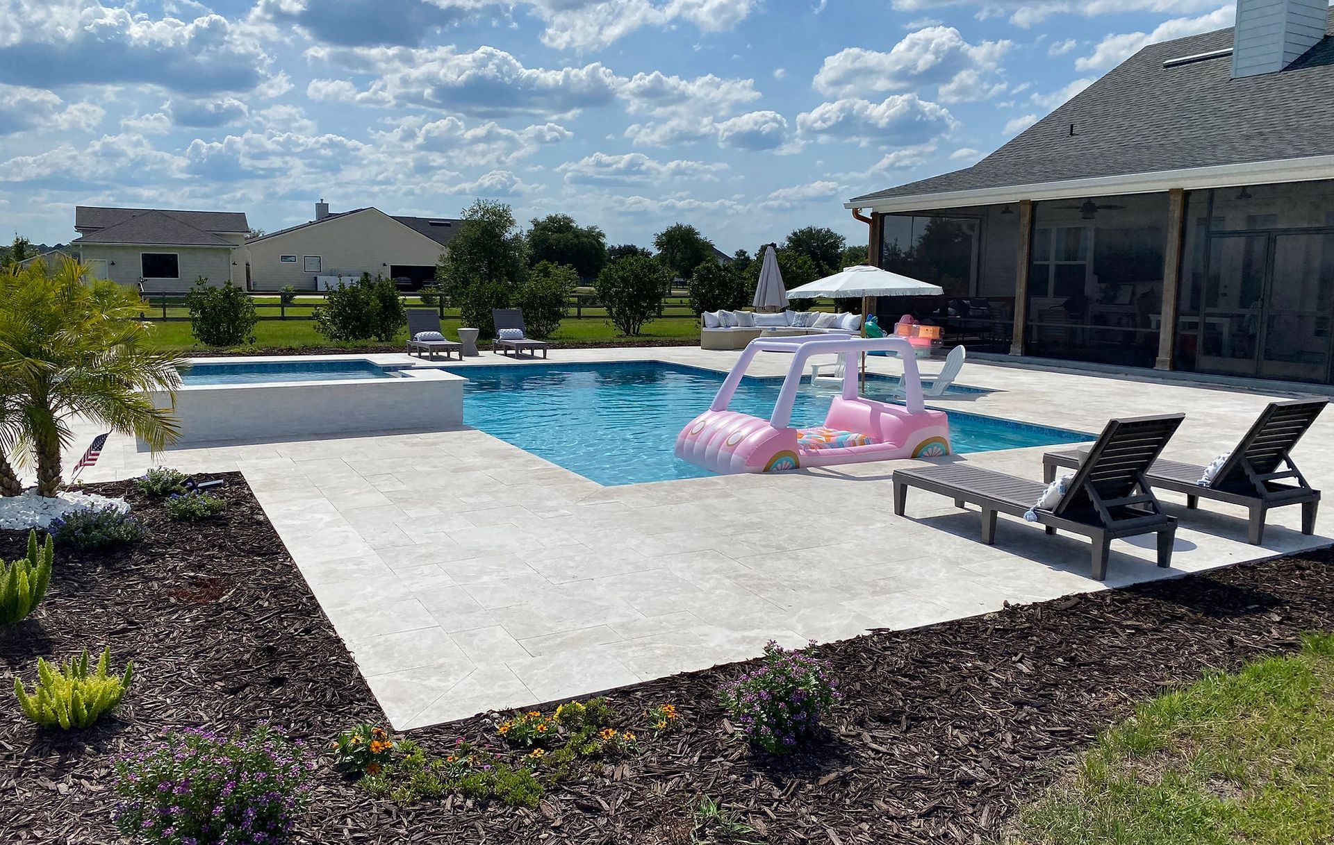 Custom concrete pool with travertine deck and lounge area built by Right Way Enclosures in Port St. Lucie, Florida.