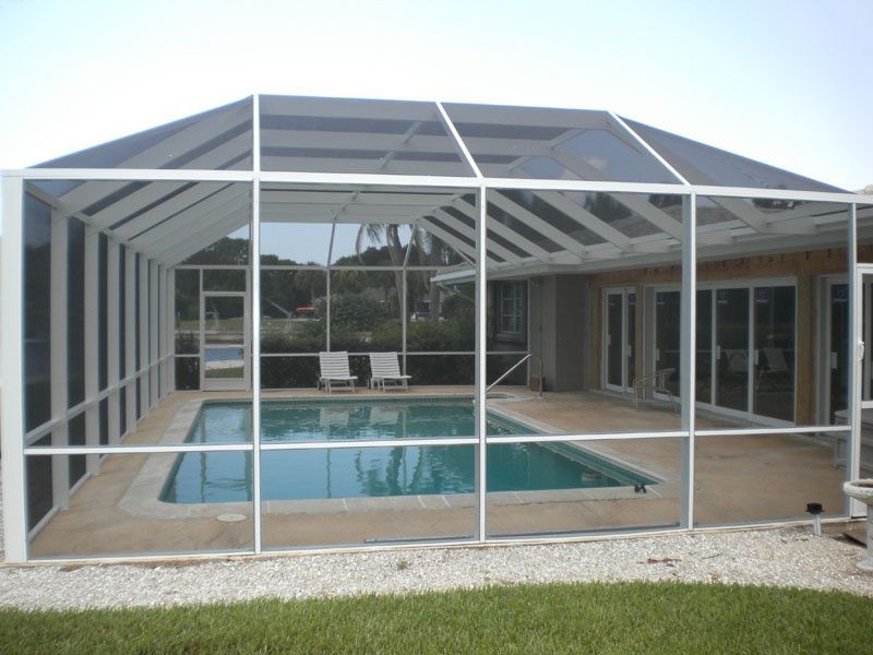 A screened in porch with a swimming pool in the background