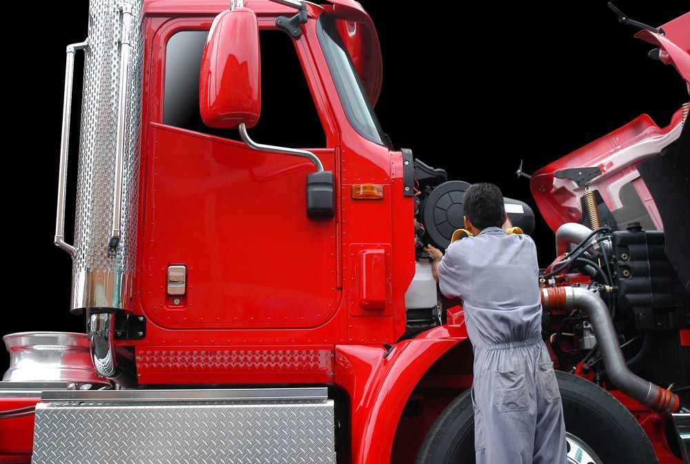 Picture of a mechanic repairing a bright red truck.