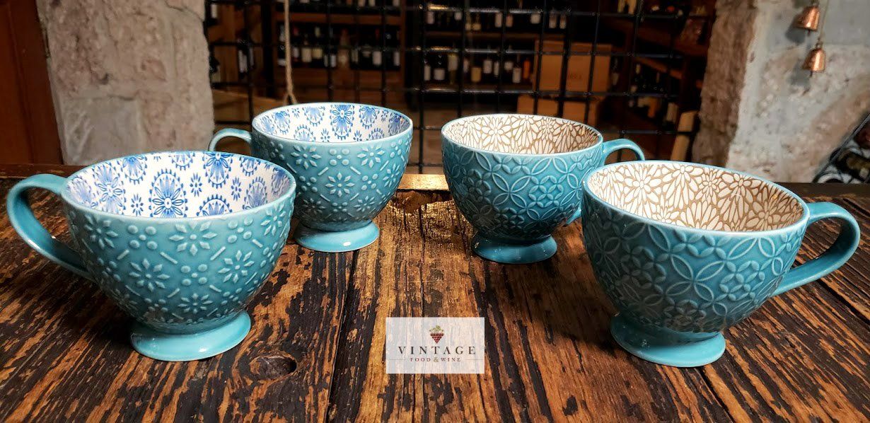 Cuatro tazas azules están sobre una mesa de madera.