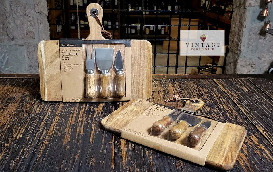 Una tabla de cortar de madera con tres cuchillos sobre ella está sobre una mesa de madera.