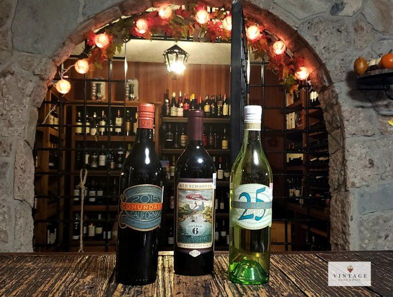 Hay tres botellas de vino sobre una mesa de madera.