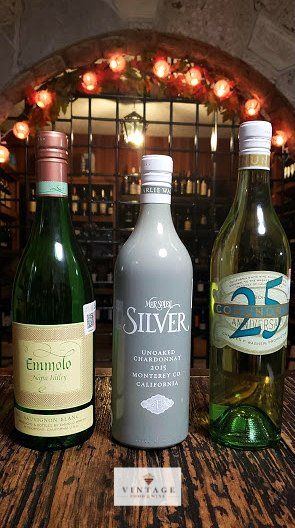 Hay tres botellas de vino sobre una mesa de madera.