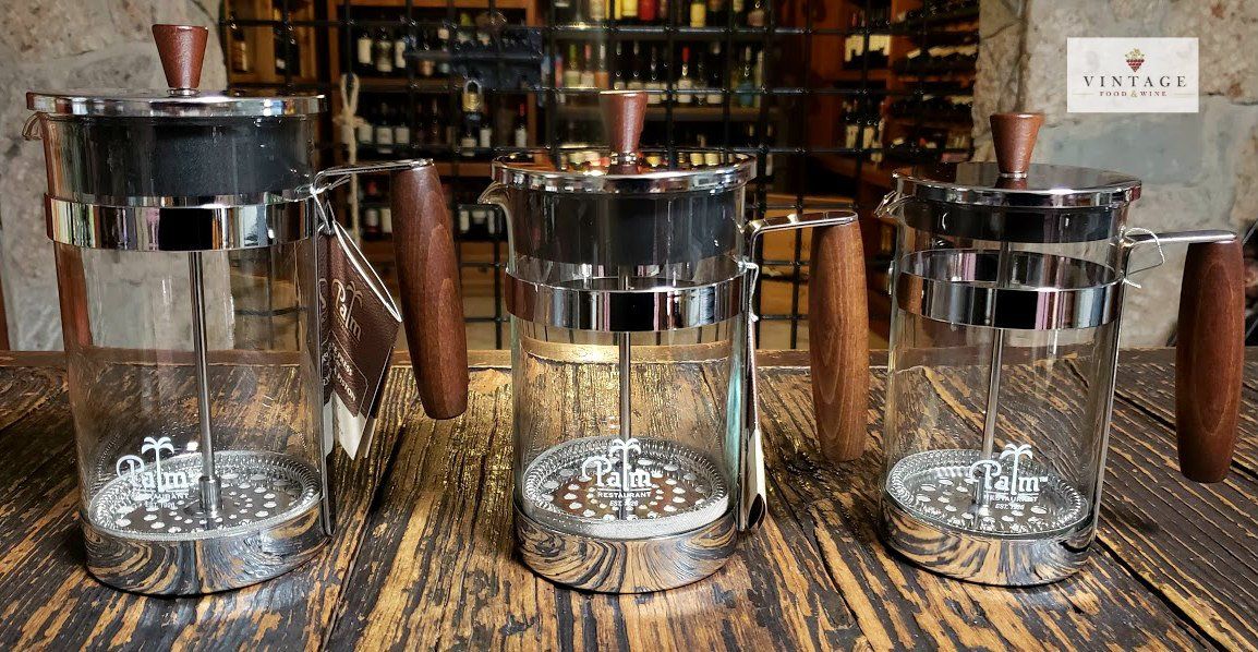 Tres cafeteras de prensa francesa están sobre una mesa de madera.