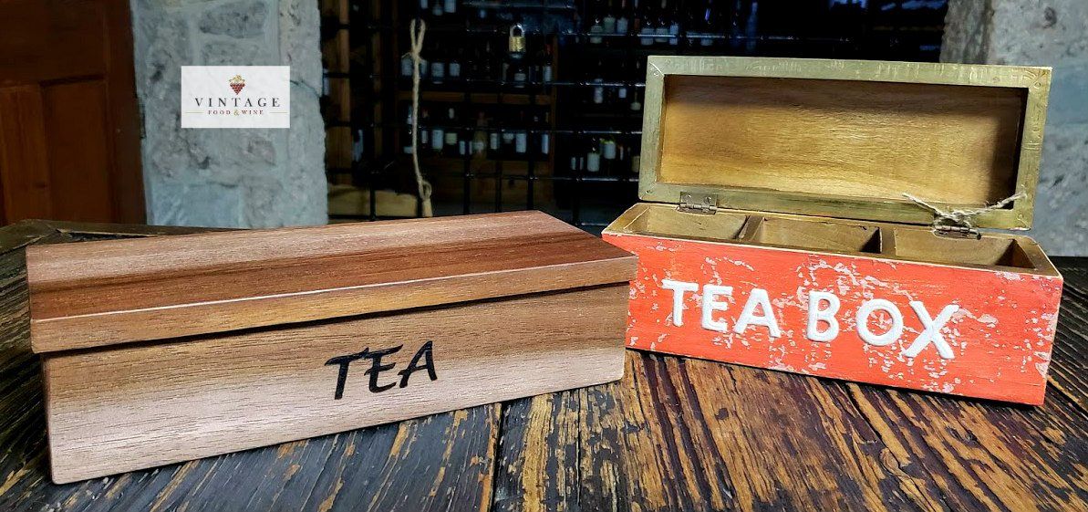 Dos cajas de té de madera están sobre una mesa de madera.