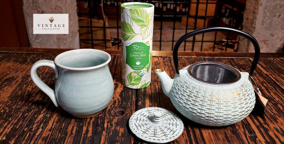 Una tetera, una taza y un posavasos están sobre una mesa de madera.