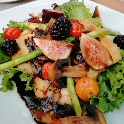 Una ensalada con frutas y verduras en un plato blanco.
